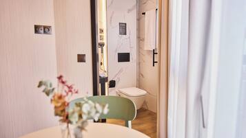 Un baño con pared de mármol, un inodoro y una zona de ducha.