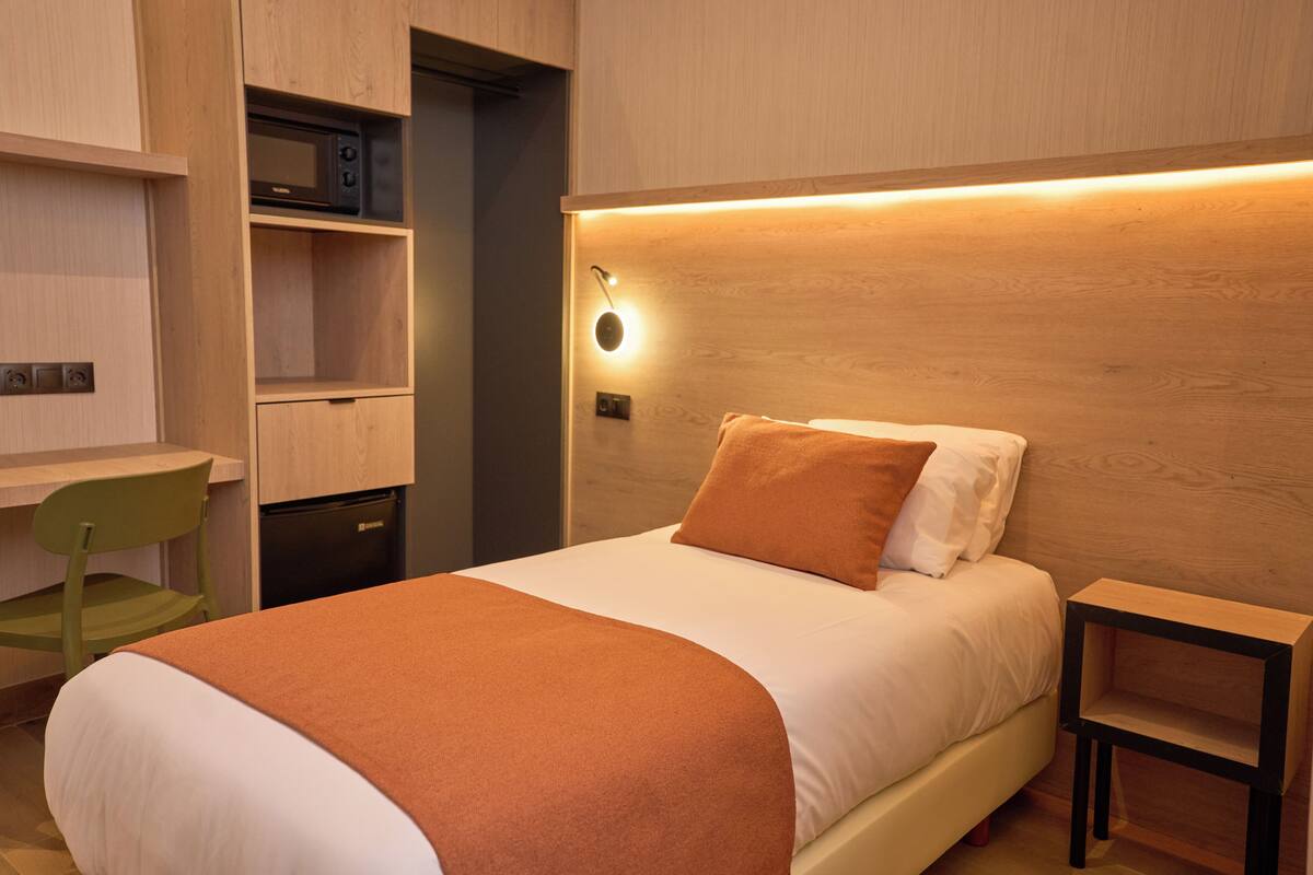 Un dormitorio con cama, escritorio y microondas.