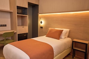 Une chambre avec un lit, un bureau et un four à micro-ondes.