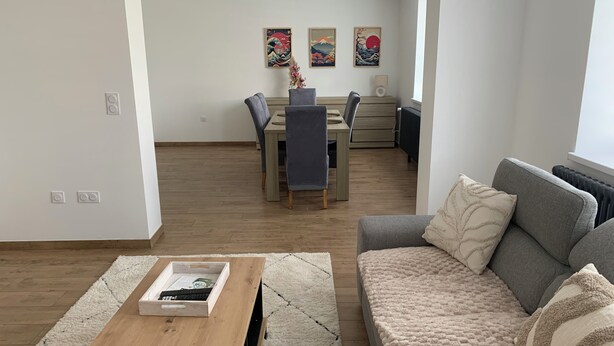 A living room with a sofa, a coffee table, and a dining area with chairs and a table. - 🌿 Cosy accommodation between nature and tranquillity (Pontpierre)