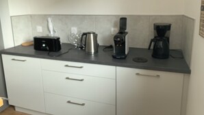 A kitchen with a coffee maker, kettle, and toaster on the counter. - 🌿 Cosy accommodation between nature and tranquillity (Pontpierre)