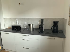 A kitchen with a coffee maker, kettle, and toaster on the counter.