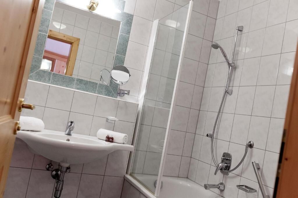 Un baño con lavamanos, espejo y ducha.