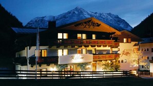 A hotel with a mountain backdrop, featuring a prominent sign with the name 'Riffelsee.'