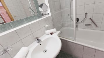 Un baño con lavamanos blanco, espejo, ducha y bañera.