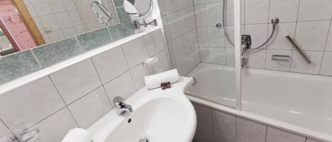 Une salle de bain avec un lavabo blanc, un miroir, une douche et une baignoire.