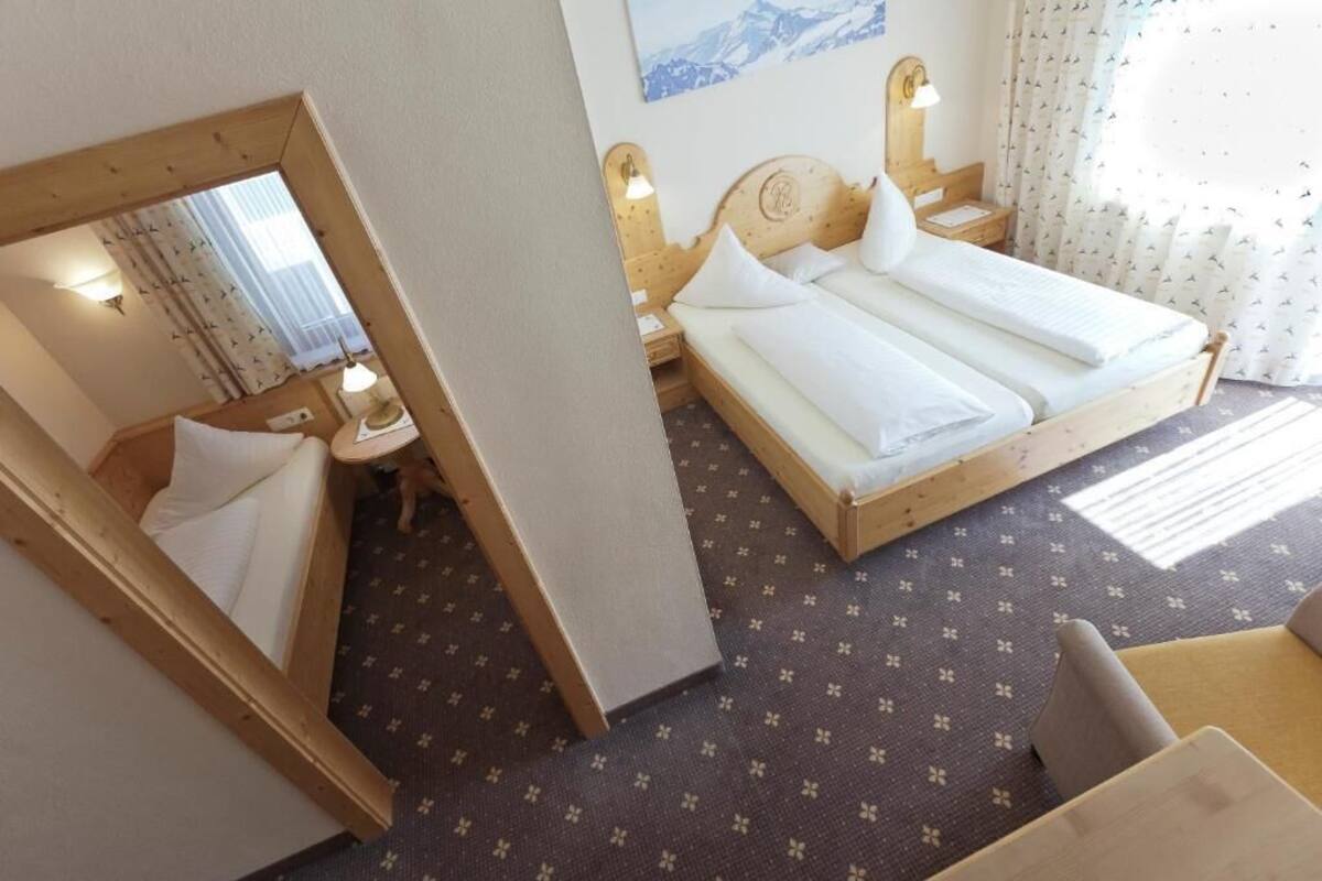 Une chambre d’hôtel avec un lit, une table de chevet, un miroir et une fenêtre avec des rideaux.