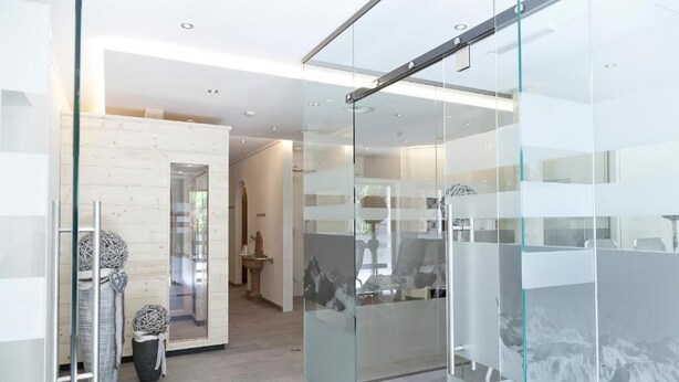 A modern interior with glass partitions, a wooden accent wall, and a tiled floor.