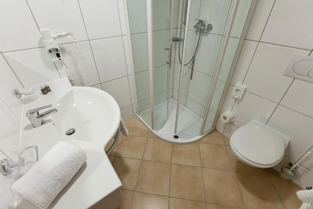 Une salle de bain avec une douche à parois de verre, un lavabo avec un miroir et des toilettes.