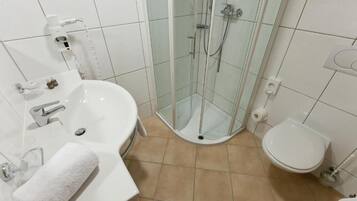 Une salle de bain avec une douche à parois de verre, un lavabo avec un miroir et des toilettes.