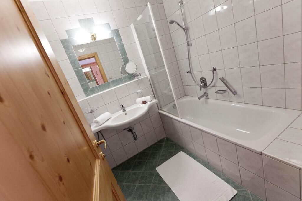 A bathroom with a sink, mirror, shower, and bathtub.