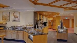 A hotel lobby with a reception desk, a buffet area, and a seating area.