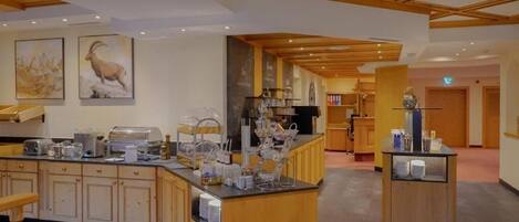 Un vestíbulo de hotel con una recepción, una zona de buffet y un área de descanso.