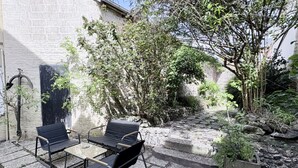 Ein Innenhof mit Steinpflaster, einem Tisch mit Stühlen und einem Blumentopf.