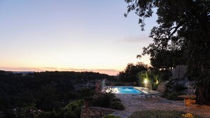 A pool area with a stone pathway, surrounded by greenery and a view of the landscape. - Nature’s Peaceful Villa: Pool,BBQ, Fragrant Garden (Rethymno)