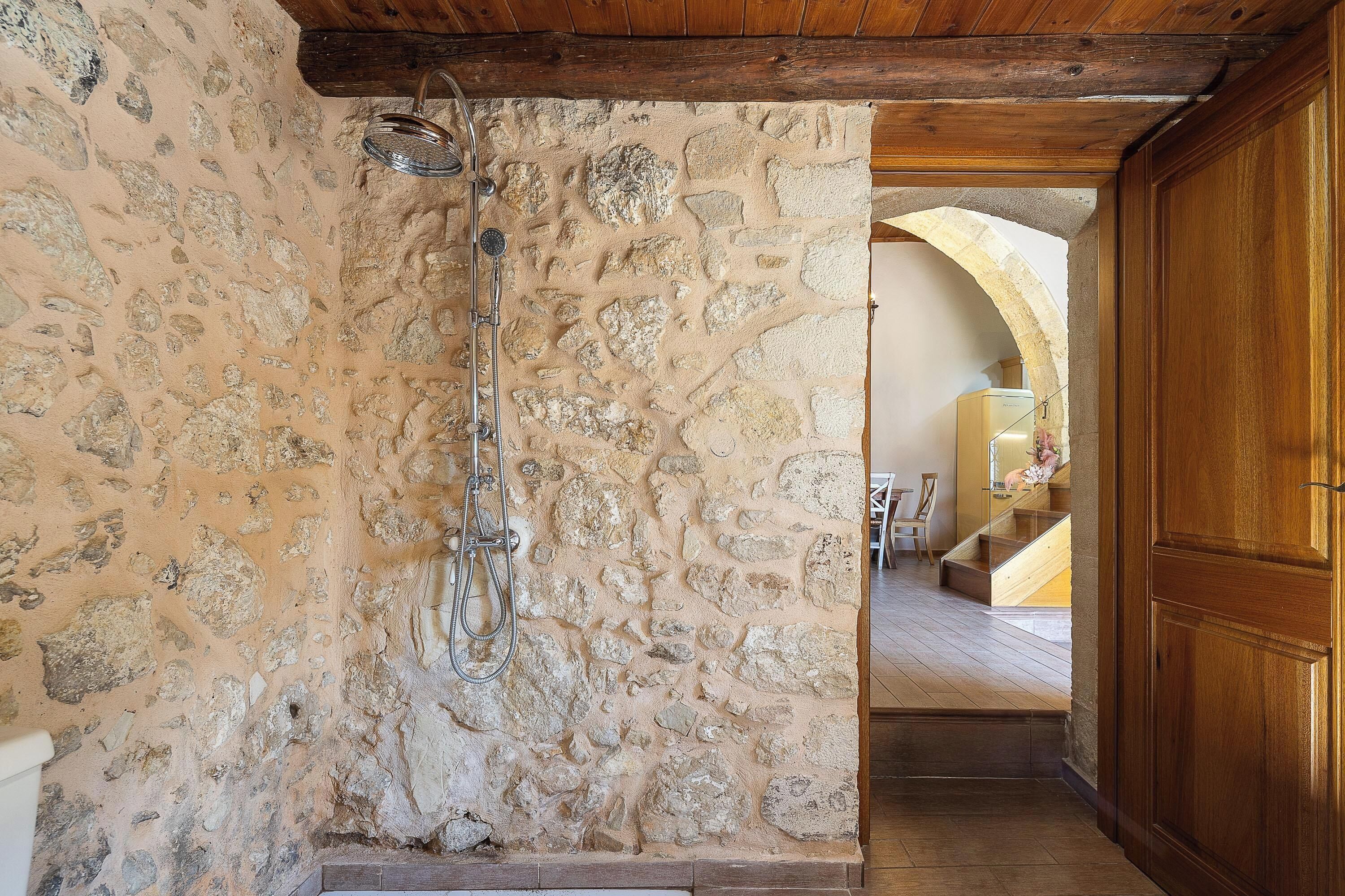 A stone shower with a wooden ceiling and a wooden door.