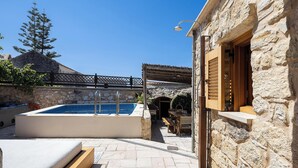 A stone building with a swimming pool, outdoor seating, and a wooden pergola. - Stone-built cottage with private pool, hot tub and spacious garden! (Rethymno)