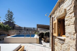 Ein Steinhaus mit Pool, Außenbereich und einer Holzpergola.
