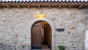 A stone building with a wooden door and an arched entrance. - Stone-built cottage with private pool, hot tub and spacious garden! (Rethymno)