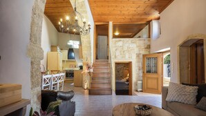 A spacious living area with a stone fireplace, wooden staircase, and a cozy seating area. - Stone-built cottage with private pool, hot tub and spacious garden! (Rethymno)