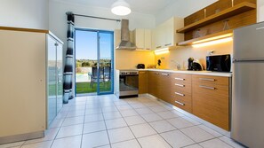 A modern kitchen with a built-in oven, microwave, and refrigerator. - Close to Sandy Beach & Amenities (Rethymno)