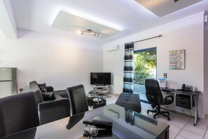 A modern office space with a glass table, black office chairs, a desk with a computer, and a television. - Close to Sandy Beach & Amenities (Rethymno)