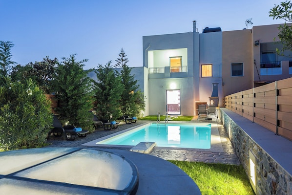 A modern two-story building with a swimming pool, outdoor seating, and a stone wall. - Close to Sandy Beach & Amenities (Rethymno)