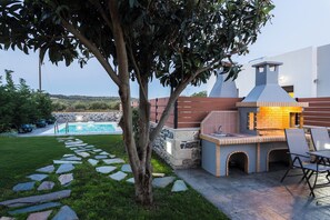 Ein Garten mit einem Kiesweg, einem Grillplatz und einem Swimmingpool.