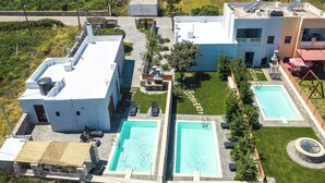 Ein Wohnhaus mit zwei Schwimmbecken, einer überdachten Terrasse und einem kleinen Garten.