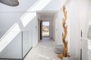Ein moderner Flur mit Glastrennwand, einer Holzskulptur und Ausblick ins Freie.