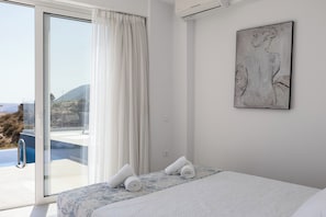 Ein Schlafzimmer mit einer großen Glasschiebetür, die auf einen Balkon führt, einem Bett mit einem gemusterten Überwurf und einem gerahmten Kunstwerk an der Wand.