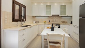 Eine moderne Küche mit weißen Schränken, einem eingebauten Backofen und einem Essbereich mit Tisch und Stühlen.