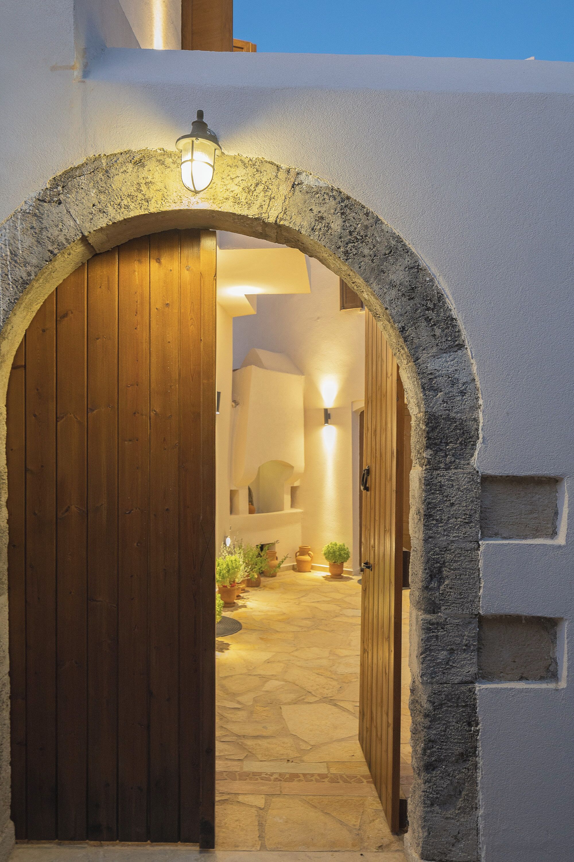 An arched doorway leading into a building with stone walls and a wooden door.