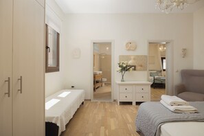 Une chambre à coucher comprenant un lit, une table de chevet, une commode, un miroir et une porte donnant sur une salle de bain.