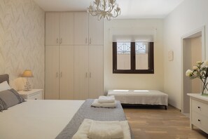Ein Schlafzimmer mit Bett, zwei Nachttischen, einem Kleiderschrank, einem Fenster mit Ausblick und einer Chandelier.