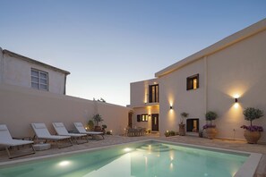 Un espace piscine avec des chaises longues et un ensemble de mobilier de jardin pour prendre les repas.
