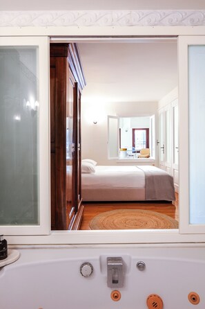 Ein Schlafzimmer mit Bett, Fenster und einem Badezimmer mit Badewanne.