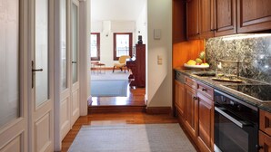 A kitchen with wooden cabinets, a granite countertop, and a built-in oven. - Charming One-Bedroom Residence in Heraklion Center (Heraklion)