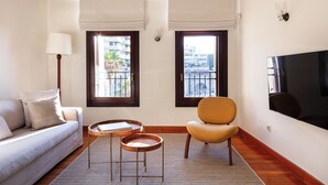 A modern living room with a sofa, armchair, coffee table, and TV. - Charming One-Bedroom Residence in Heraklion Center (Heraklion)