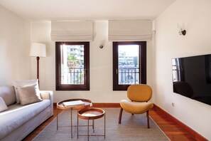 Ein modernes Wohnzimmer mit Sofa, Sessel, Couchtisch und Fernseher.