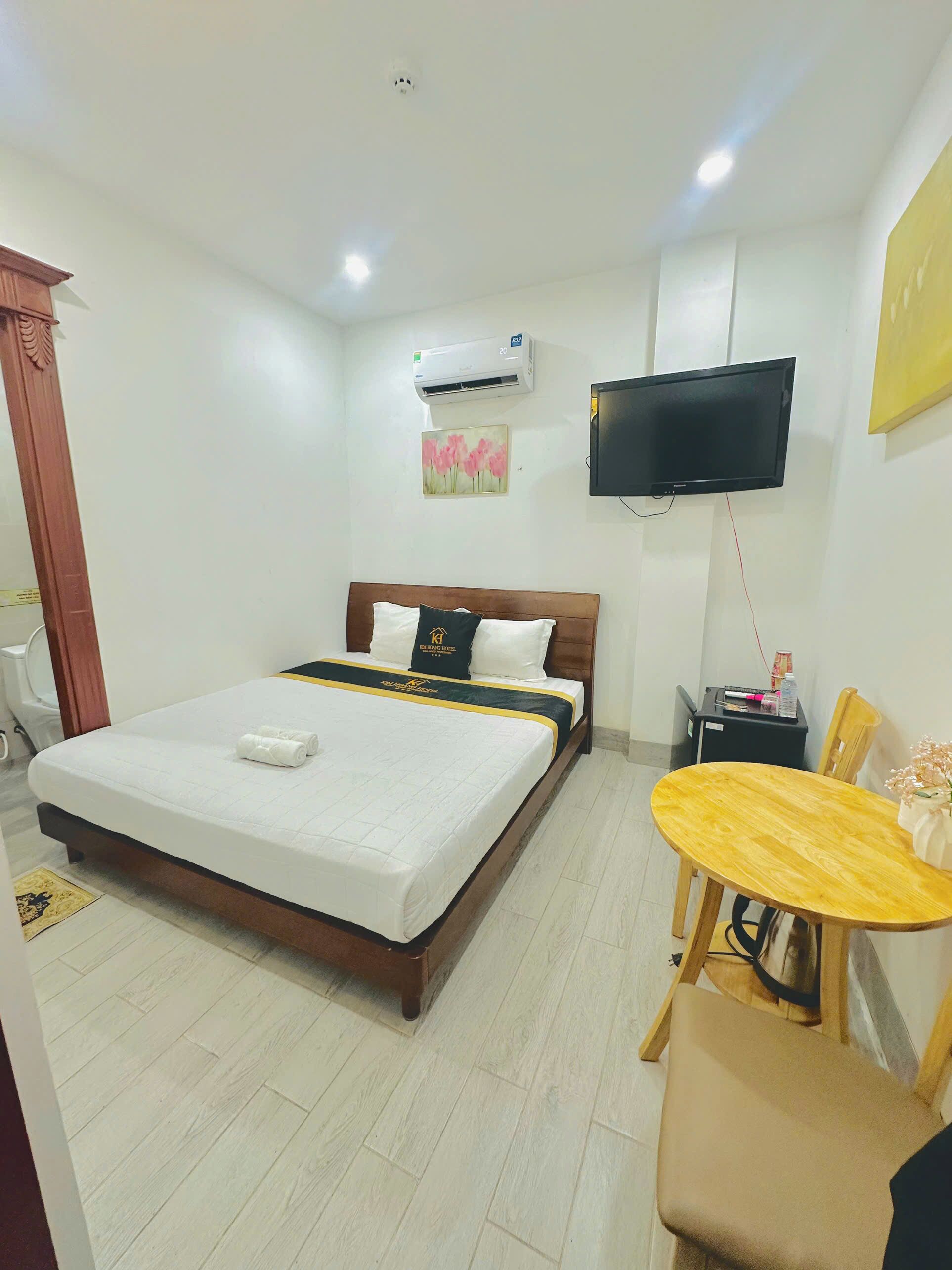 A hotel room with a bed, a television, a small table, and a chair.