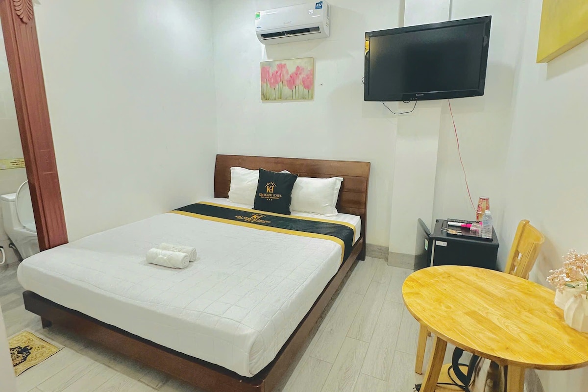 A hotel room with a bed, a television, a small table, and a chair.