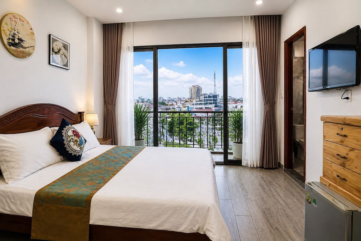 Een hotelkamer met een groot bed, een televisie, een houten dressoir en een balkon met uitzicht op de stad.