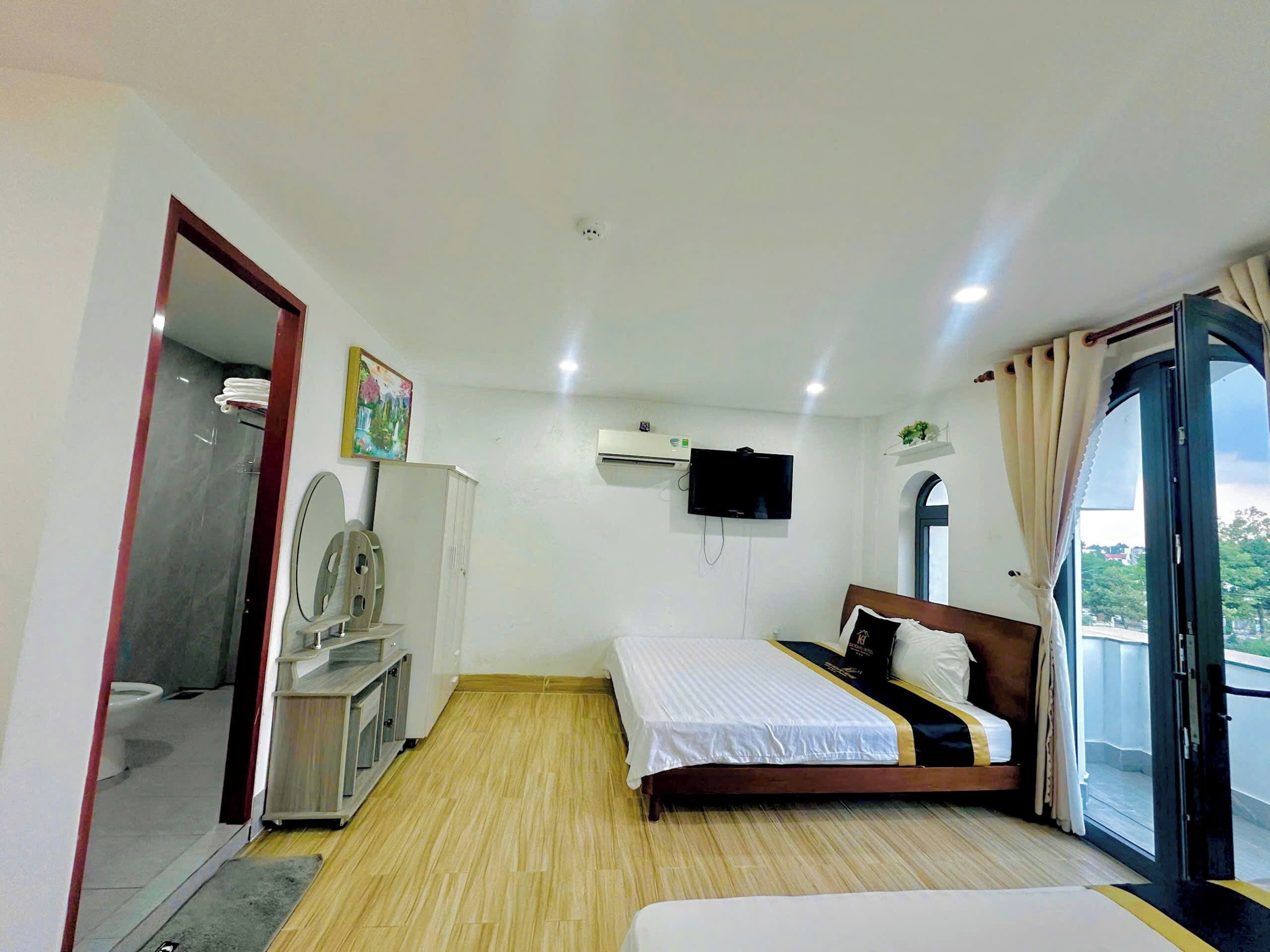 A hotel room with a bed, a TV, a wardrobe, and a bathroom.