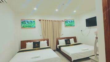 A hotel room with two beds, a TV, and artwork on the walls.