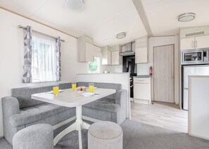 A compact kitchen with a microwave, stove, and cabinets. - Gold 4 Bedroom Caravan with parking and decking (Skegness)