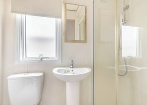 Un baño con inodoro, lavabo, espejo y ducha.