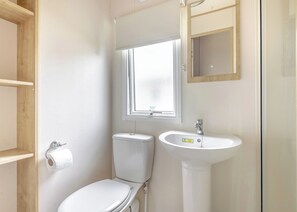A small bathroom with a toilet, sink, and window. - Gold 4 Bedroom Caravan with parking and decking (Skegness)
