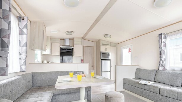 Un intérieur de camping-car moderne comprenant un coin repas, une kitchenette et un espace salon.