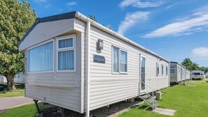 Une maison mobile dotée d’un toit plat, de grandes fenêtres et d’une enseigne indiquant « Summer Breeze Deluxe ».